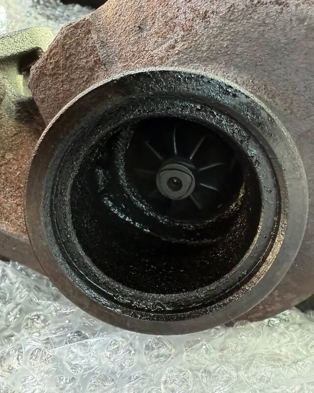 Wlot sprężarki starej turbosprężarki pokryty olejem i sadzą, w środku wirnik